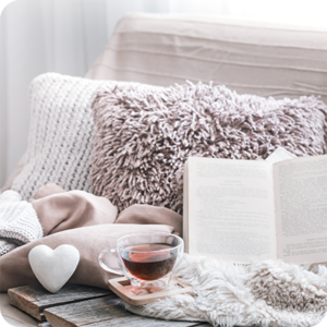 cosy picture of fluffy cushions, book,warm drink